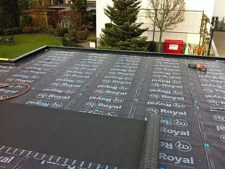 Plat dak met de onderlaag deels uitgerold over het dakvlak