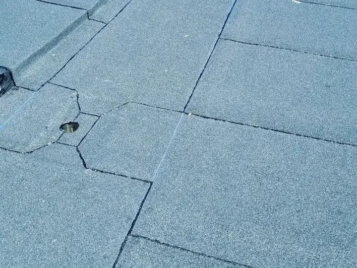 Close-up van een grijs granulaatdak rond een afvoer