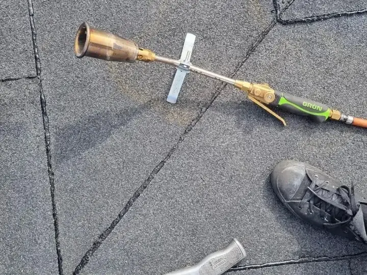 Gasbrander en gereedschap liggen klaar op een grijs granulaatdak