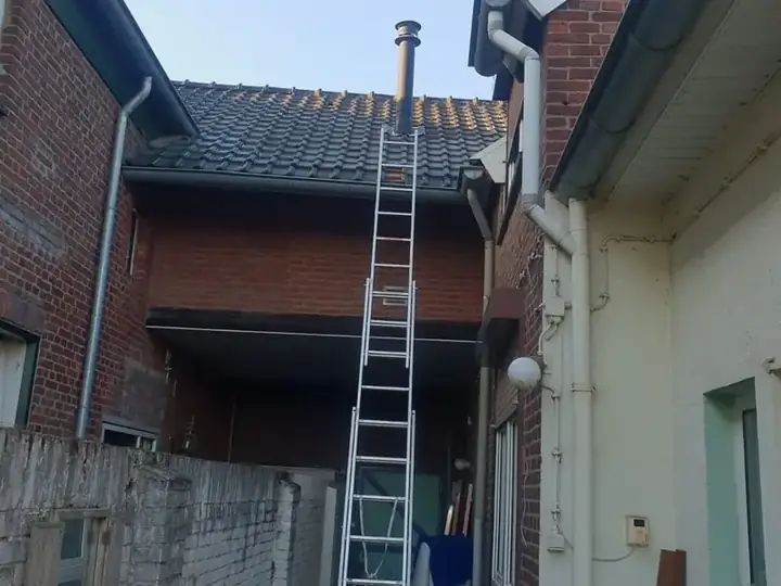 Plat dak met ladder tegen de gevel, dakkapel en schoorsteen